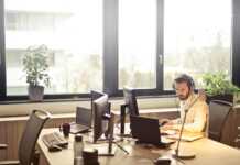 man with headphones facing computer monitor