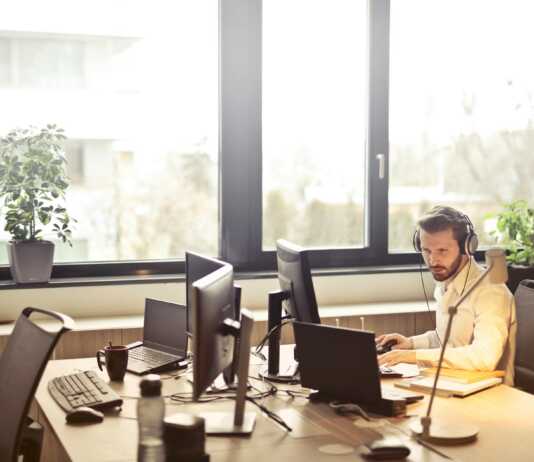man with headphones facing computer monitor